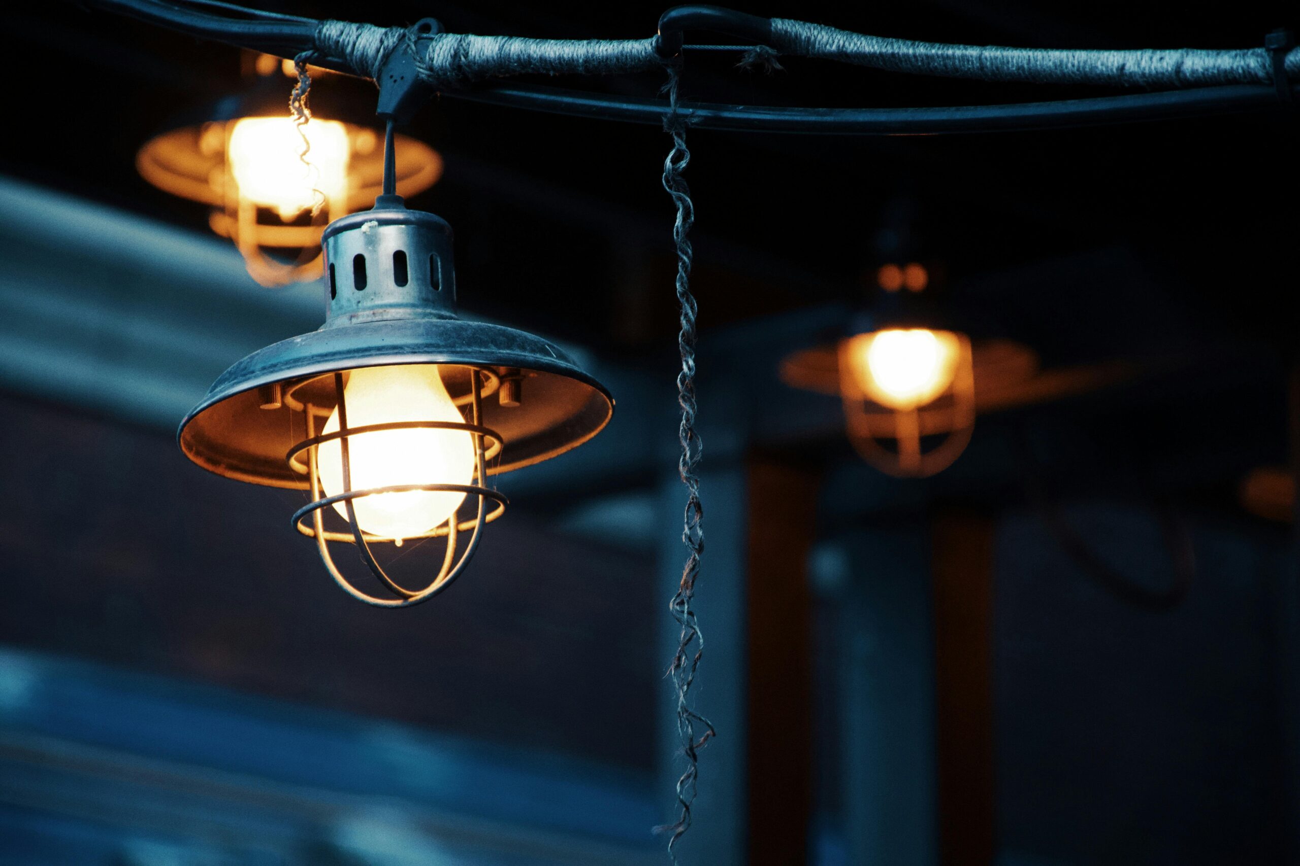 Close-up of vintage industrial light fixtures hanging with a warm glow, creating an atmospheric effect.